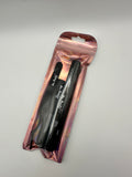 Black eyeliner pencil in a rose gold packaging on a gray background
