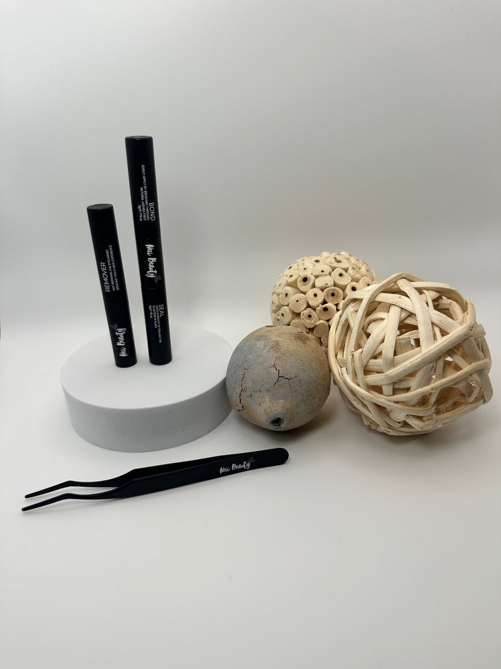 Black eyeliner pencil, tweezers, and decorative balls on a white background