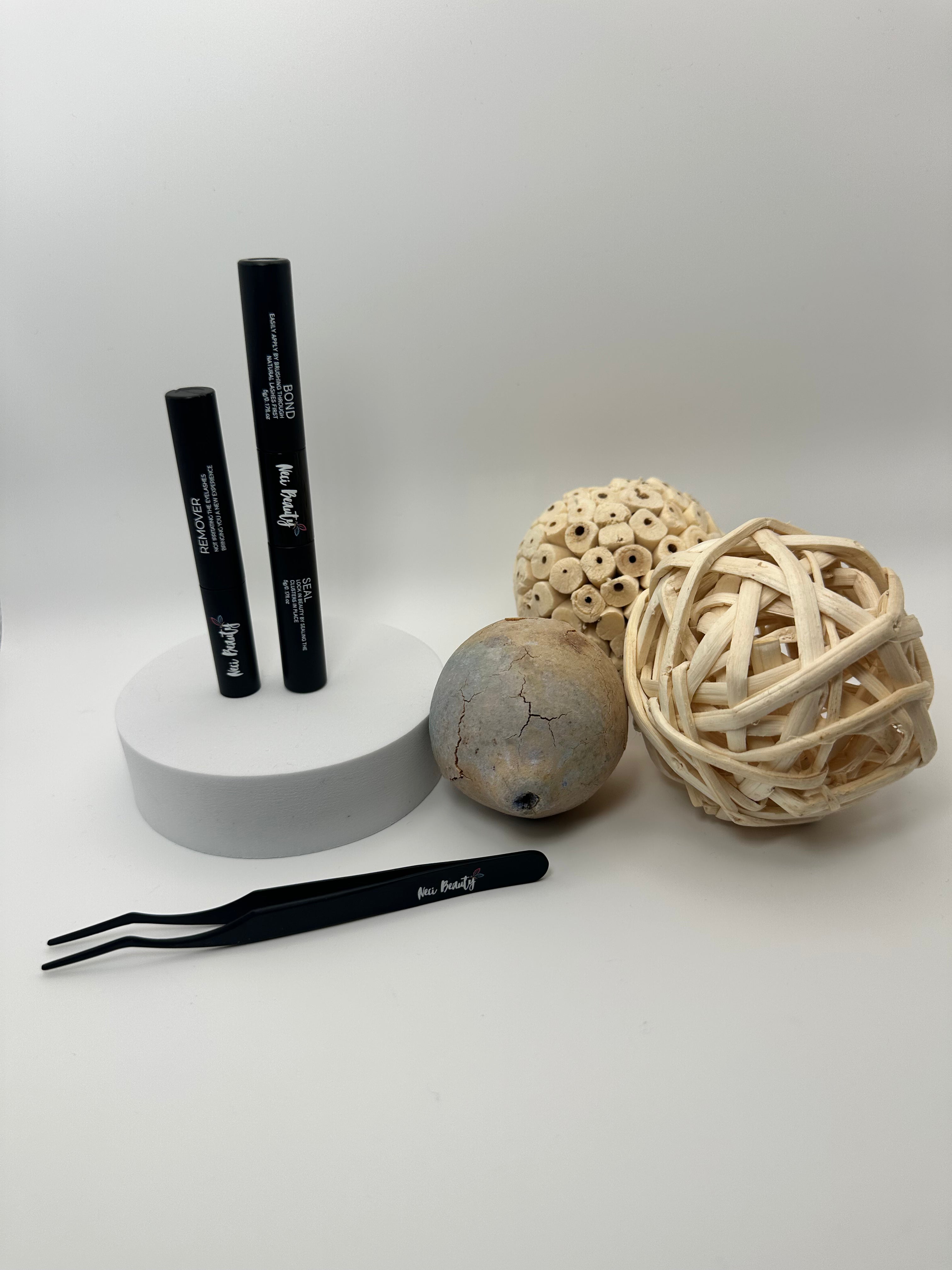 Black eyeliner pencil, tweezers, and decorative balls on a white background