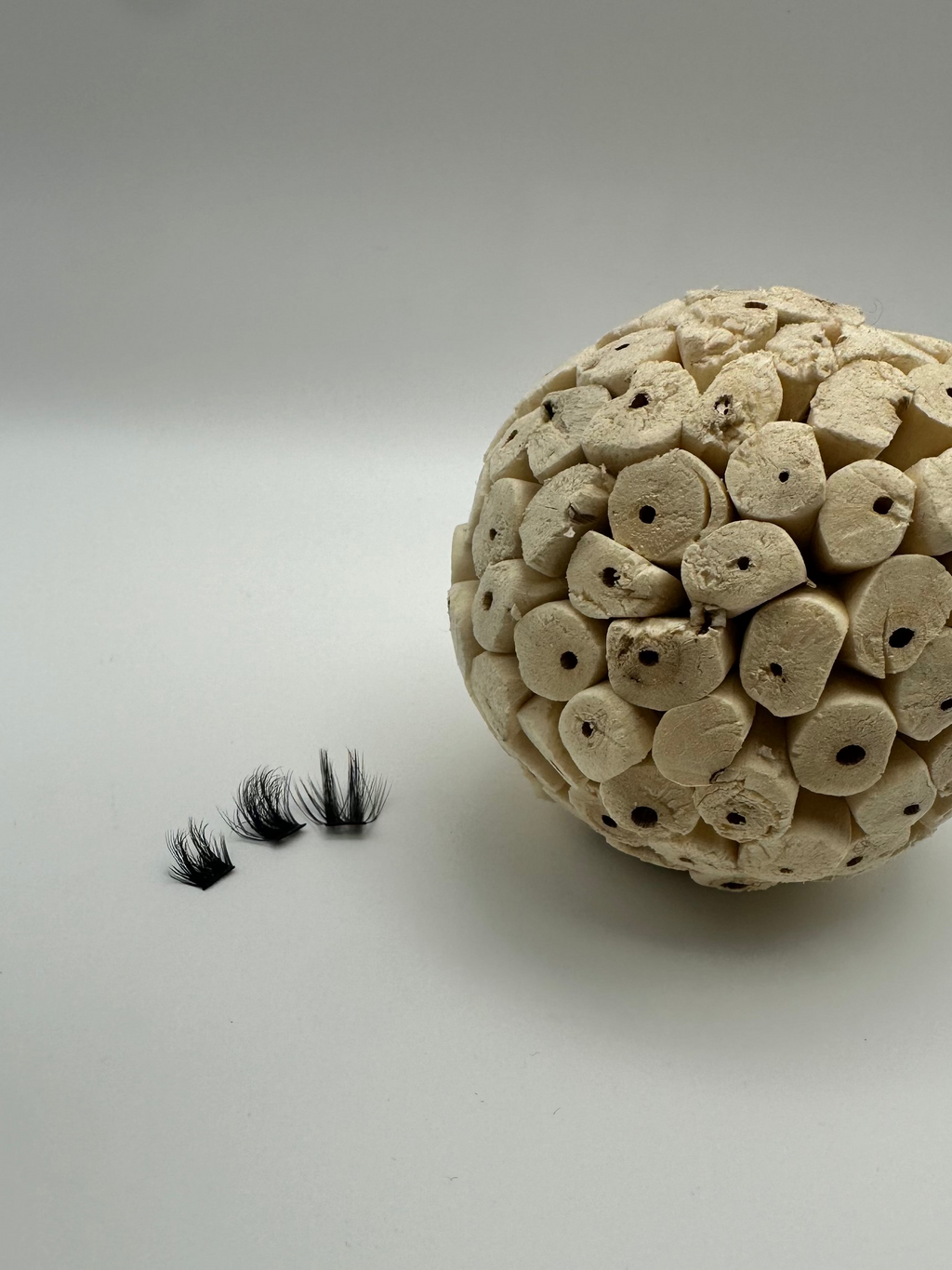 Ceramic ball with small black objects on a plain background