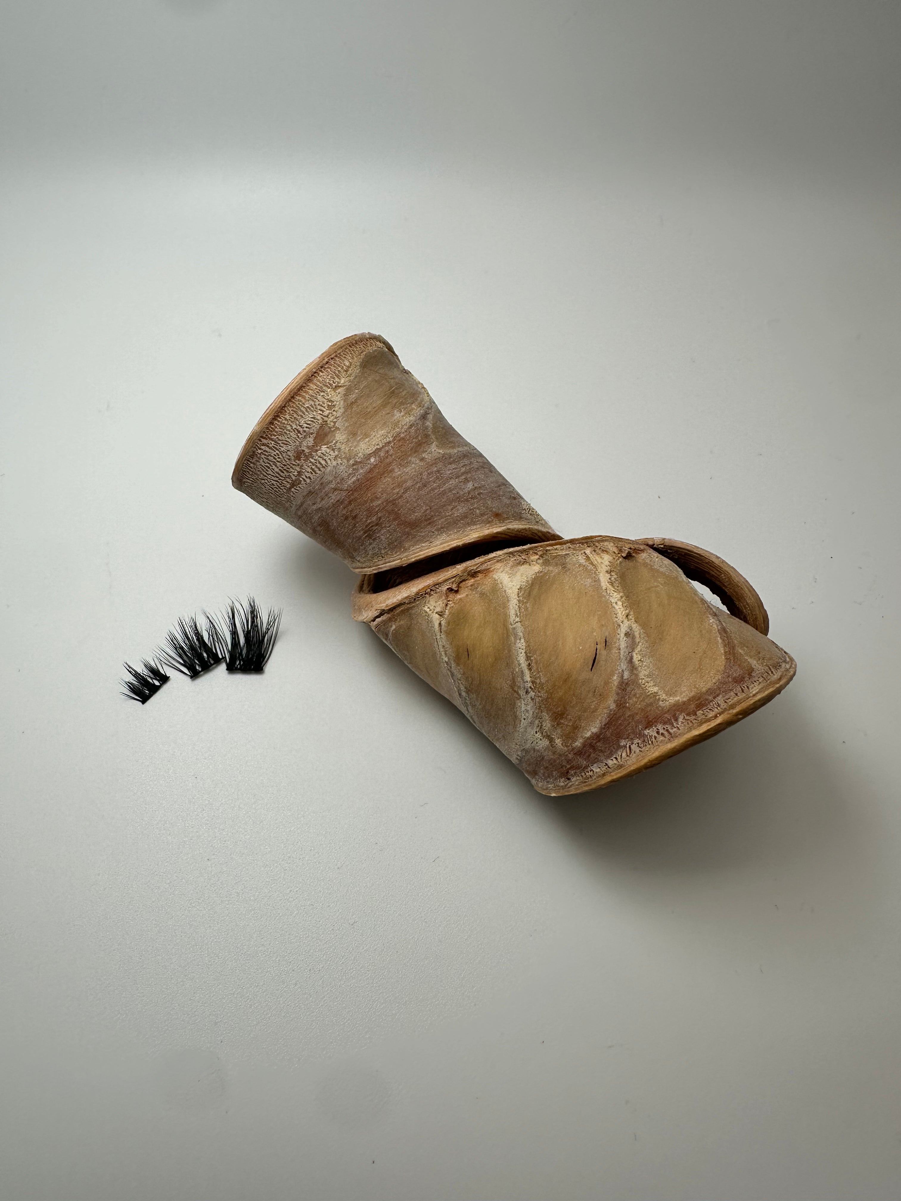 Ceramic container with false eyelashes on a light gray background
