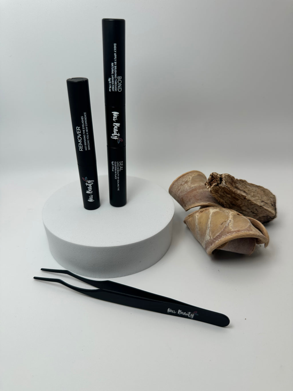 Two black makeup brushes on a white stand with a brown paper bag on a white background